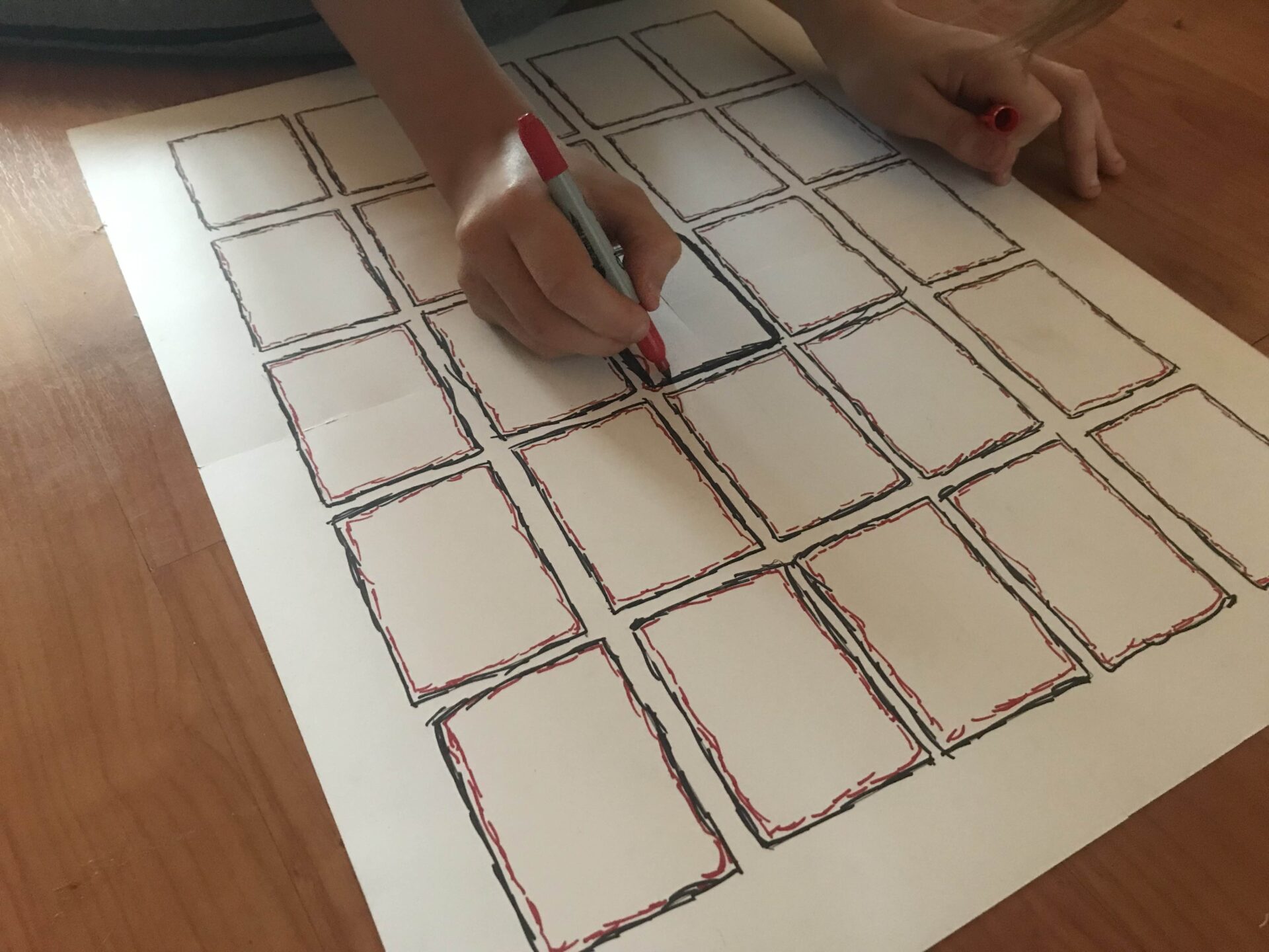 He is now embellishing the border of each card space with black and red Sharpie.