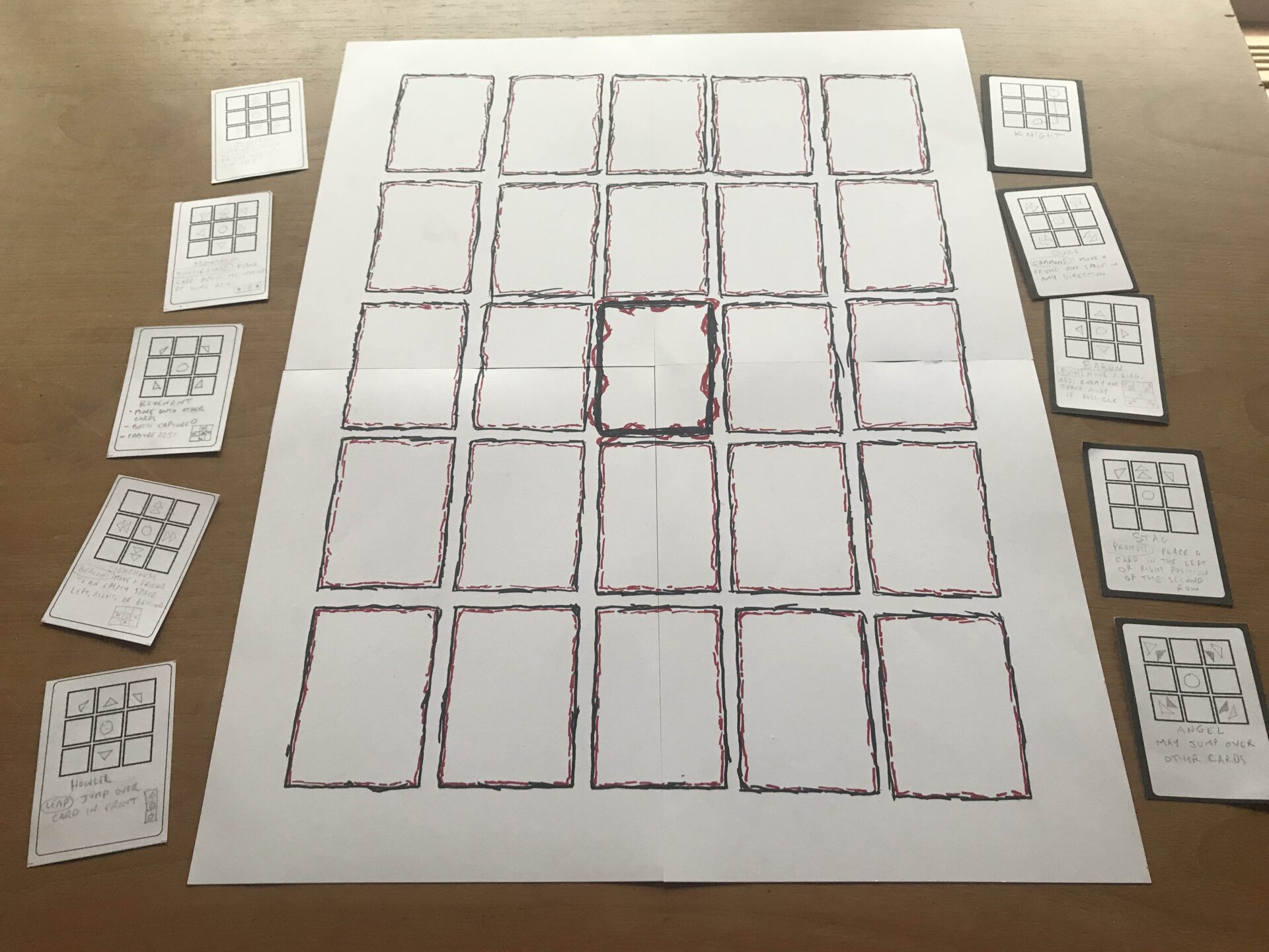 The finished playmat, with some cards on either side. Each space on the grid is outlined with rough black and red "scratchy" art that looks like a cross between vines and crackling electricity.